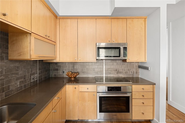 340 S Lafayette St Unit 201, Denver, CO 80209 - kitchen featuring appliances with stainless steel finishes, light brown cabinetry, tasteful backsplash, and dark countertops