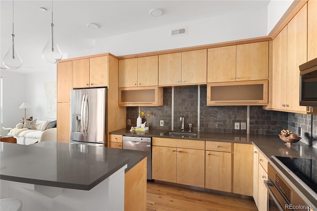 340 S Lafayette St Unit 201, Denver, CO 80209 - kitchen featuring appliances with stainless steel finishes, a sink, dark countertops, backsplash, and light brown cabinetry