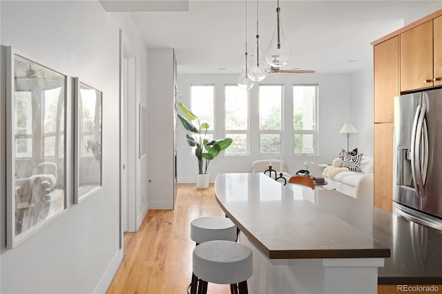 340 S Lafayette St Unit 201, Denver, CO 80209 - kitchen featuring stainless steel refrigerator with ice dispenser, a kitchen bar, light wood-type flooring, baseboards, and dark countertops