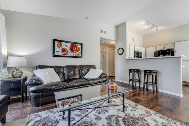 living room featuring dark wood-type flooring, lofted ceiling, and rail lighting