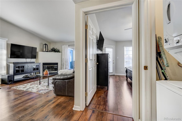 living room featuring stacked washer and clothes dryer, dark hardwood / wood-style flooring, and vaulted ceiling