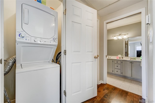 clothes washing area featuring stacked washer and dryer, sink, and dark hardwood / wood-style flooring