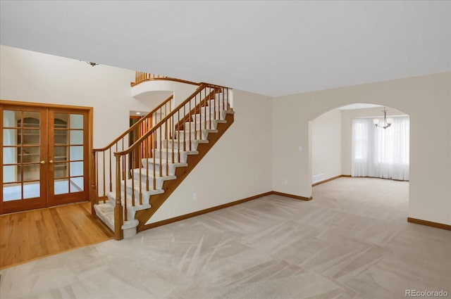 stairway featuring carpet flooring, french doors, and an inviting chandelier