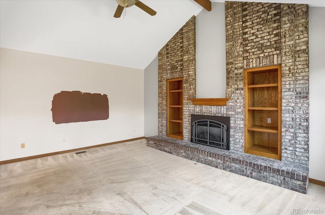 unfurnished living room with carpet flooring, built in shelves, ceiling fan, a brick fireplace, and beamed ceiling