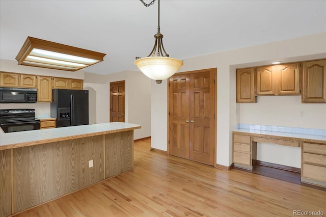 kitchen featuring black appliances, decorative light fixtures, light hardwood / wood-style floors, and kitchen peninsula