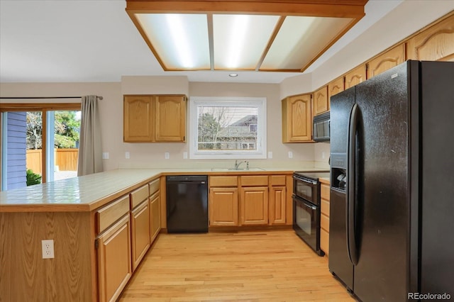 kitchen featuring black appliances, kitchen peninsula, sink, and light hardwood / wood-style flooring