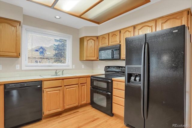 kitchen with black appliances, light hardwood / wood-style floors, and sink