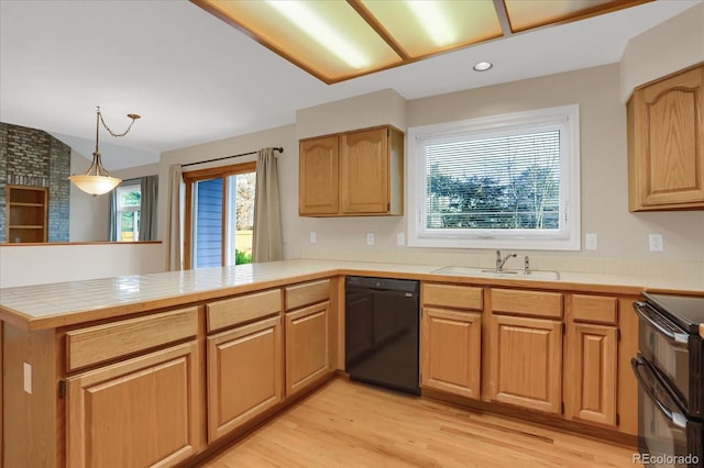 kitchen featuring black appliances, sink, light wood-type flooring, decorative light fixtures, and kitchen peninsula