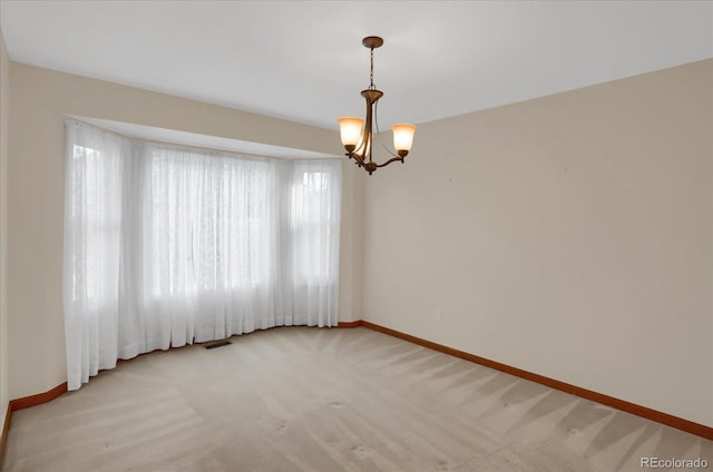 empty room featuring a chandelier, light carpet, and a wealth of natural light