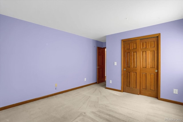 unfurnished bedroom featuring light carpet and a closet