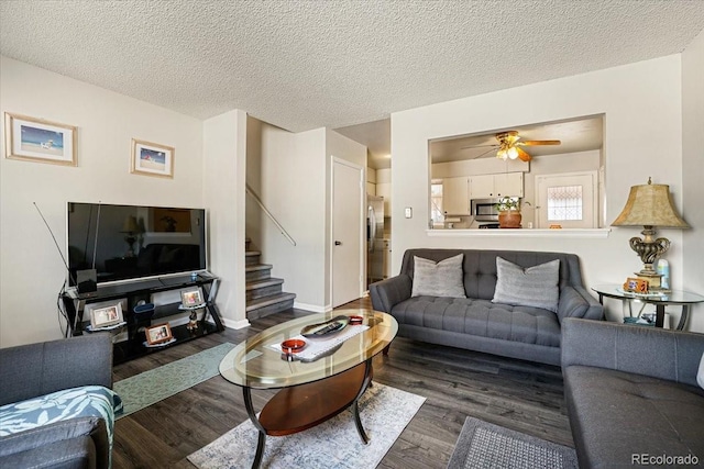 living room featuring dark wood-type flooring, ceiling fan, and a textured ceiling