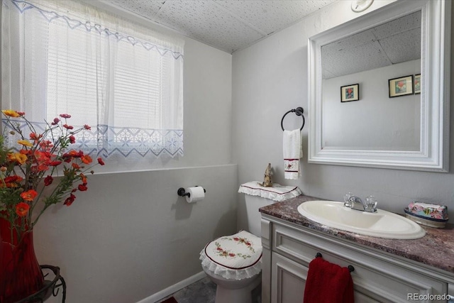 bathroom featuring vanity, toilet, and a drop ceiling