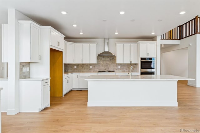 9322 Quaker St, Arvada, CO 80007 - kitchen with gas cooktop, a sink, double oven, light wood-type flooring, and wall chimney range hood