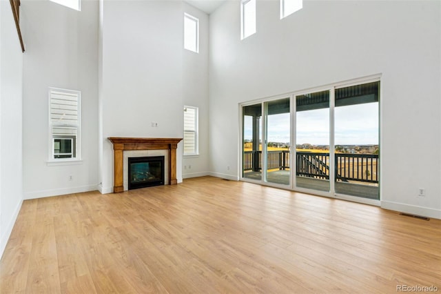 9322 Quaker St, Arvada, CO 80007 - unfurnished living room with a glass covered fireplace, baseboards, light wood finished floors, and visible vents