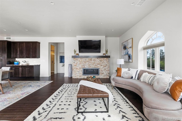 living room with a stone fireplace and dark hardwood / wood-style floors