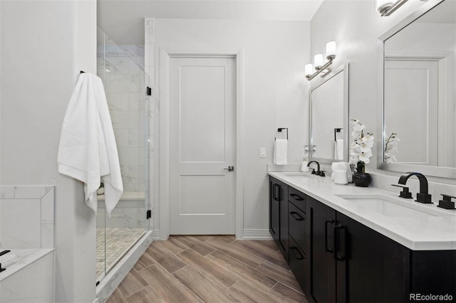 bathroom featuring a shower with door, wood-type flooring, and dual bowl vanity