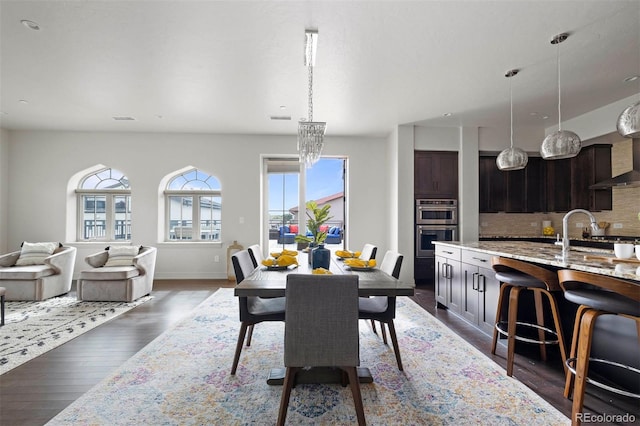 dining room with an inviting chandelier, sink, and dark hardwood / wood-style flooring