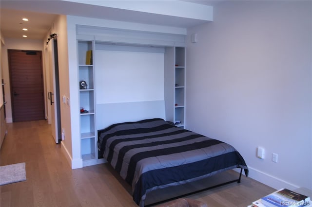 bedroom featuring a barn door and dark wood-type flooring