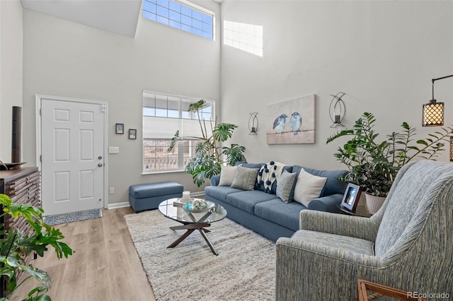 living room with a towering ceiling and light hardwood / wood-style flooring