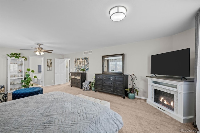 bedroom featuring ceiling fan, light carpet, and a fireplace