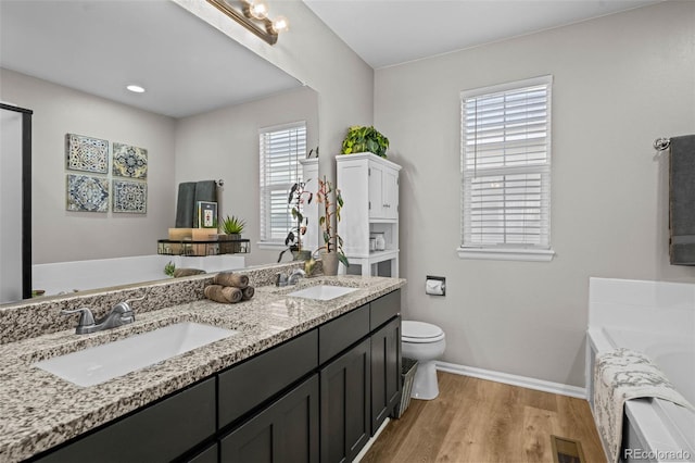 bathroom with vanity, hardwood / wood-style flooring, a tub, and toilet