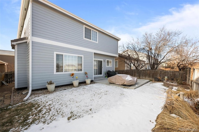 snow covered rear of property with a patio area