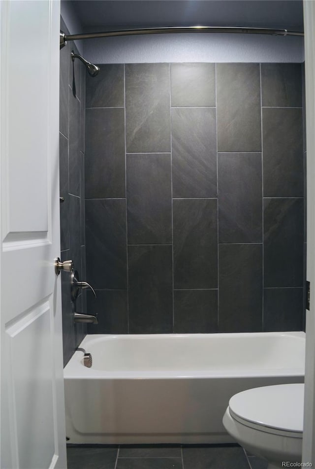 bathroom with tile patterned flooring, tiled shower / bath combo, and toilet