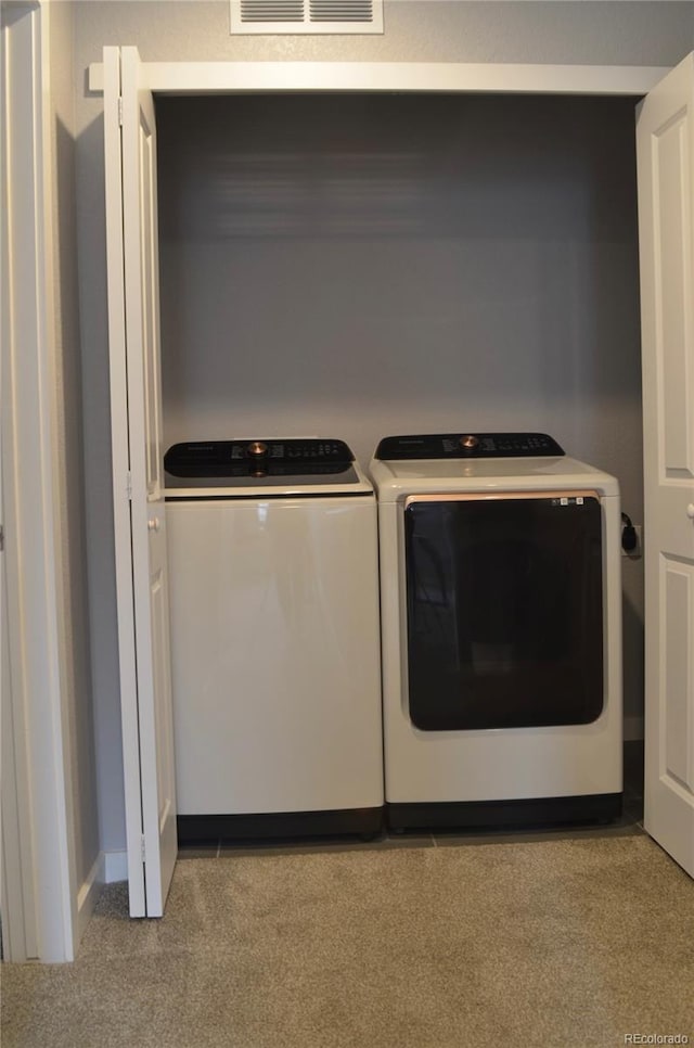 laundry area featuring light carpet and washing machine and dryer