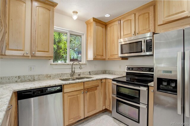 7552 Garland St, Arvada, CO 80005 - kitchen with appliances with stainless steel finishes, a sink, light brown cabinetry, light stone counters, and recessed lighting