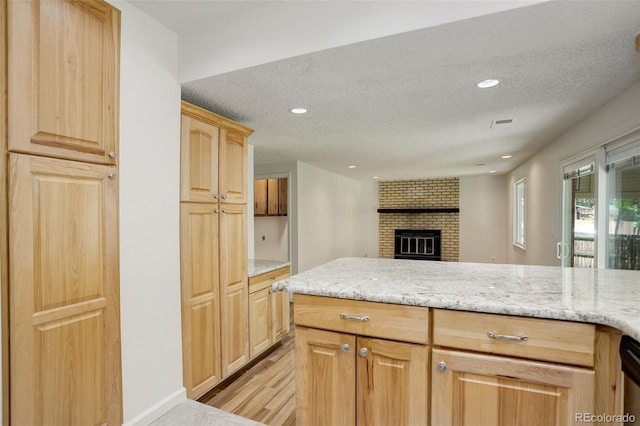 7552 Garland St, Arvada, CO 80005 - kitchen with a textured ceiling, light stone counters, light wood-type flooring, open floor plan, and recessed lighting