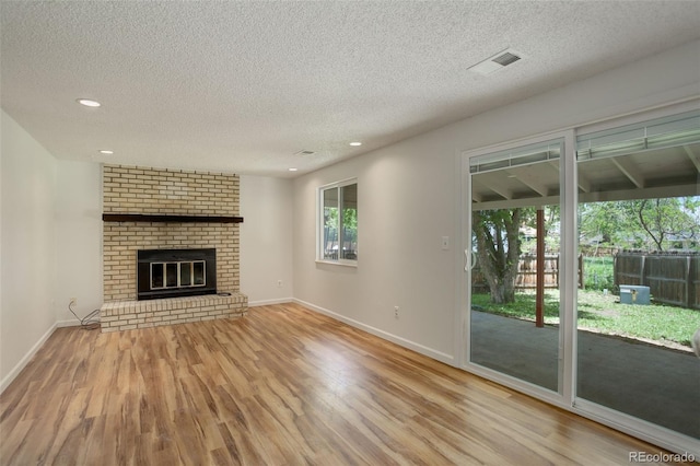 7552 Garland St, Arvada, CO 80005 - unfurnished living room with wood finished floors, a textured ceiling, baseboards, recessed lighting, and a fireplace