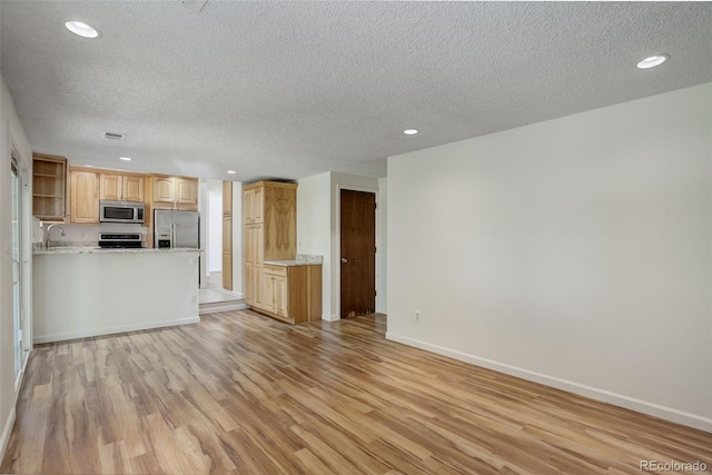 7552 Garland St, Arvada, CO 80005 - unfurnished living room featuring light wood-type flooring, a textured ceiling, recessed lighting, baseboards, and a sink