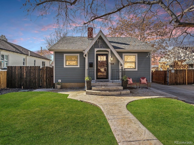 view of front of home with a chimney, fence, and a front lawn