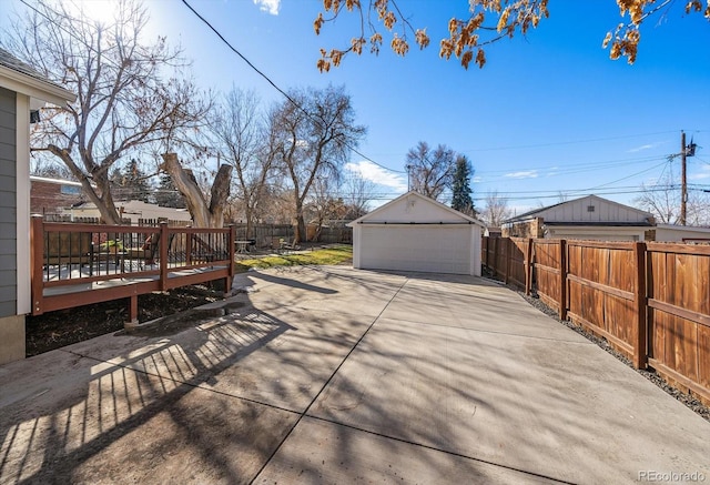 exterior space featuring a garage, fence private yard, a wooden deck, and an outdoor structure