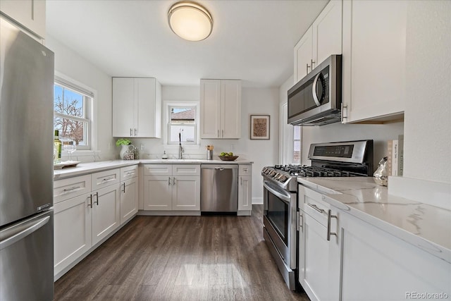 kitchen with stainless steel appliances, white cabinetry, a sink, and dark wood-style floors