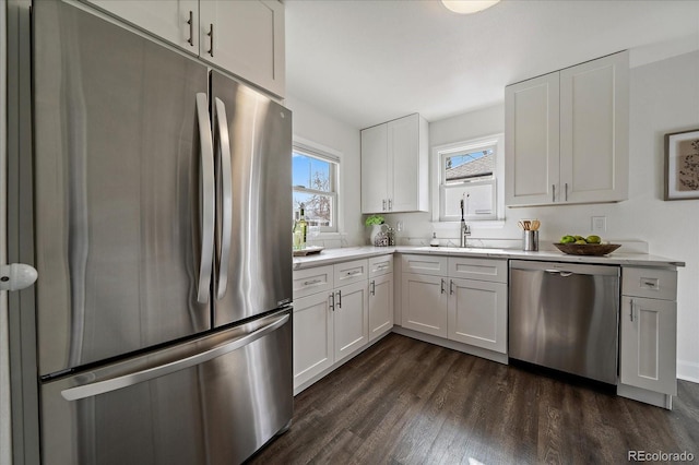 kitchen featuring stainless steel appliances, a sink, white cabinets, light countertops, and dark wood-style floors