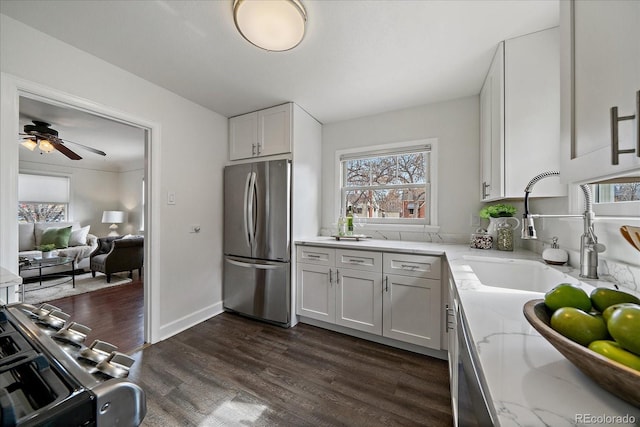 kitchen featuring dark wood-type flooring, freestanding refrigerator, white cabinetry, a sink, and light stone countertops