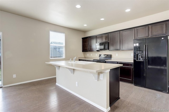 467 S 36th Ave, Brighton, CO 80601 - kitchen featuring black appliances, a sink, an island with sink, dark brown cabinetry, and a kitchen bar
