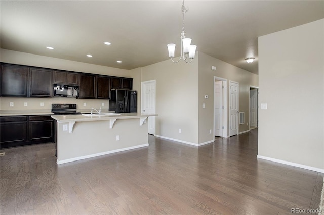 467 S 36th Ave, Brighton, CO 80601 - kitchen featuring black appliances, dark wood-style floors, a breakfast bar, light countertops, and recessed lighting