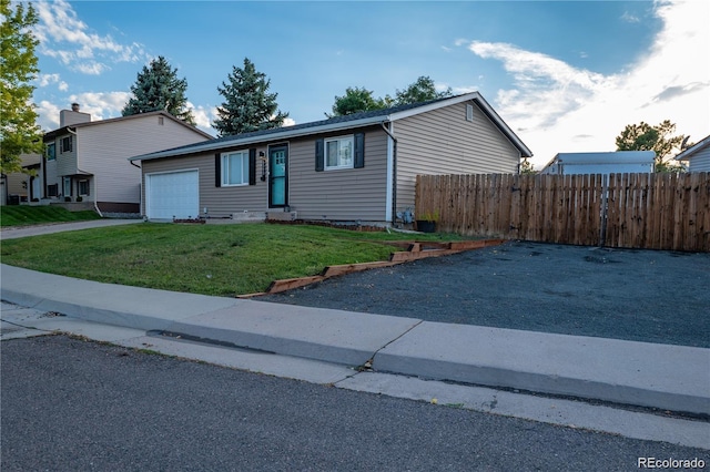 view of front of home with a garage, a front yard, fence, and driveway