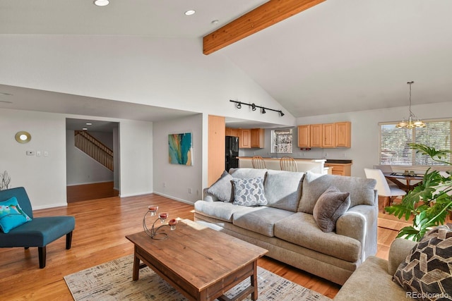 living room featuring beam ceiling, high vaulted ceiling, light hardwood / wood-style flooring, and a chandelier