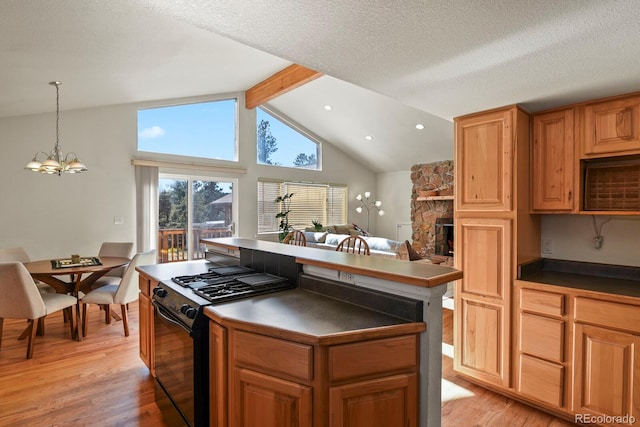 kitchen featuring black gas range, lofted ceiling with beams, a fireplace, and light wood-type flooring