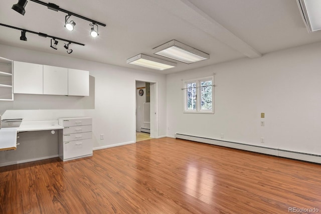 interior space with light hardwood / wood-style floors, white cabinetry, and a baseboard heating unit