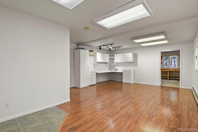 kitchen with white cabinetry, built in desk, and wood-type flooring