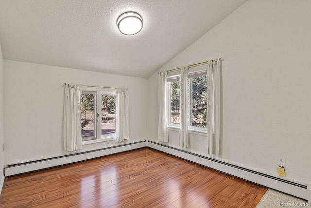 empty room featuring a textured ceiling, wood-type flooring, vaulted ceiling, and a baseboard heating unit