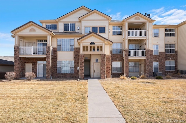 townhome / multi-family property featuring brick siding, central air condition unit, and a front lawn