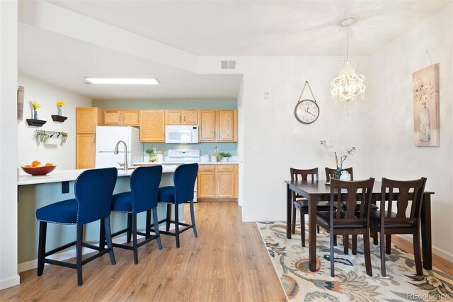 5735 N Genoa Way Unit 11-205, Aurora, CO 80019 - kitchen with white appliances, visible vents, light countertops, a kitchen breakfast bar, and light wood-type flooring