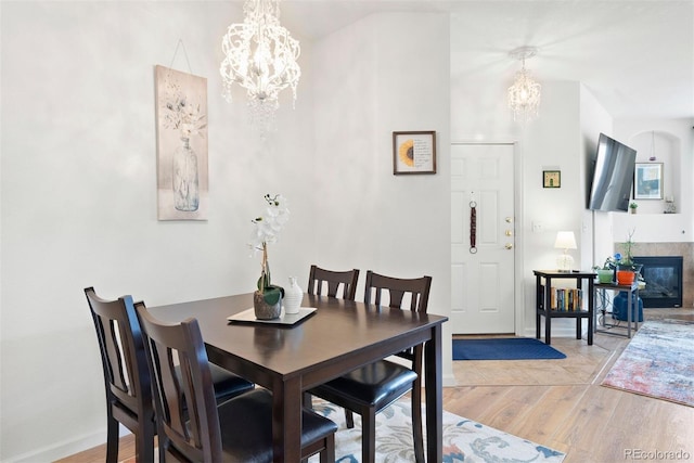 5735 N Genoa Way Unit 11-205, Aurora, CO 80019 - dining room with a glass covered fireplace, an inviting chandelier, light wood-style floors, and baseboards