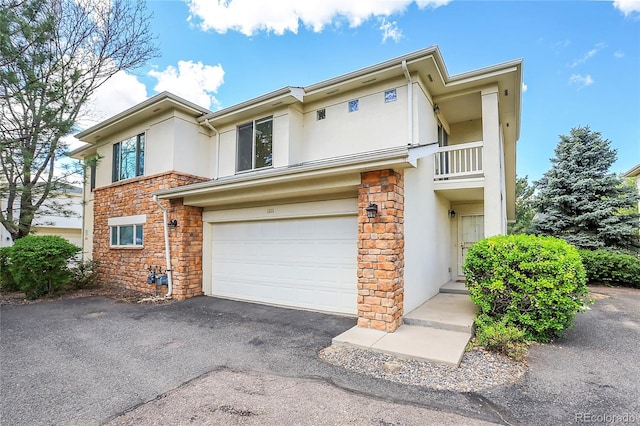 view of front of home with stone siding, stucco siding, an attached garage, driveway, and a balcony