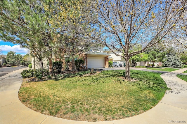 view of property hidden behind natural elements with brick siding, driveway, an attached garage, and a front yard